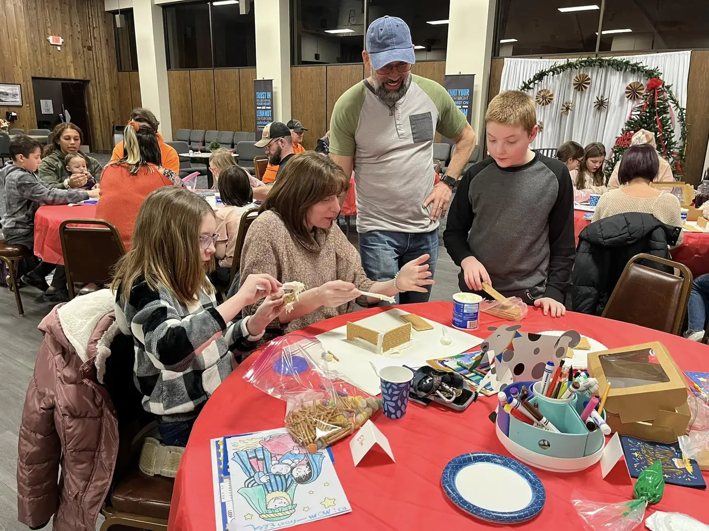 Families and children making holiday crafts together at tables, with parents helping